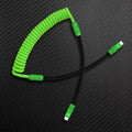 Green coiled USB-C cable with black straight wire on carbon texture